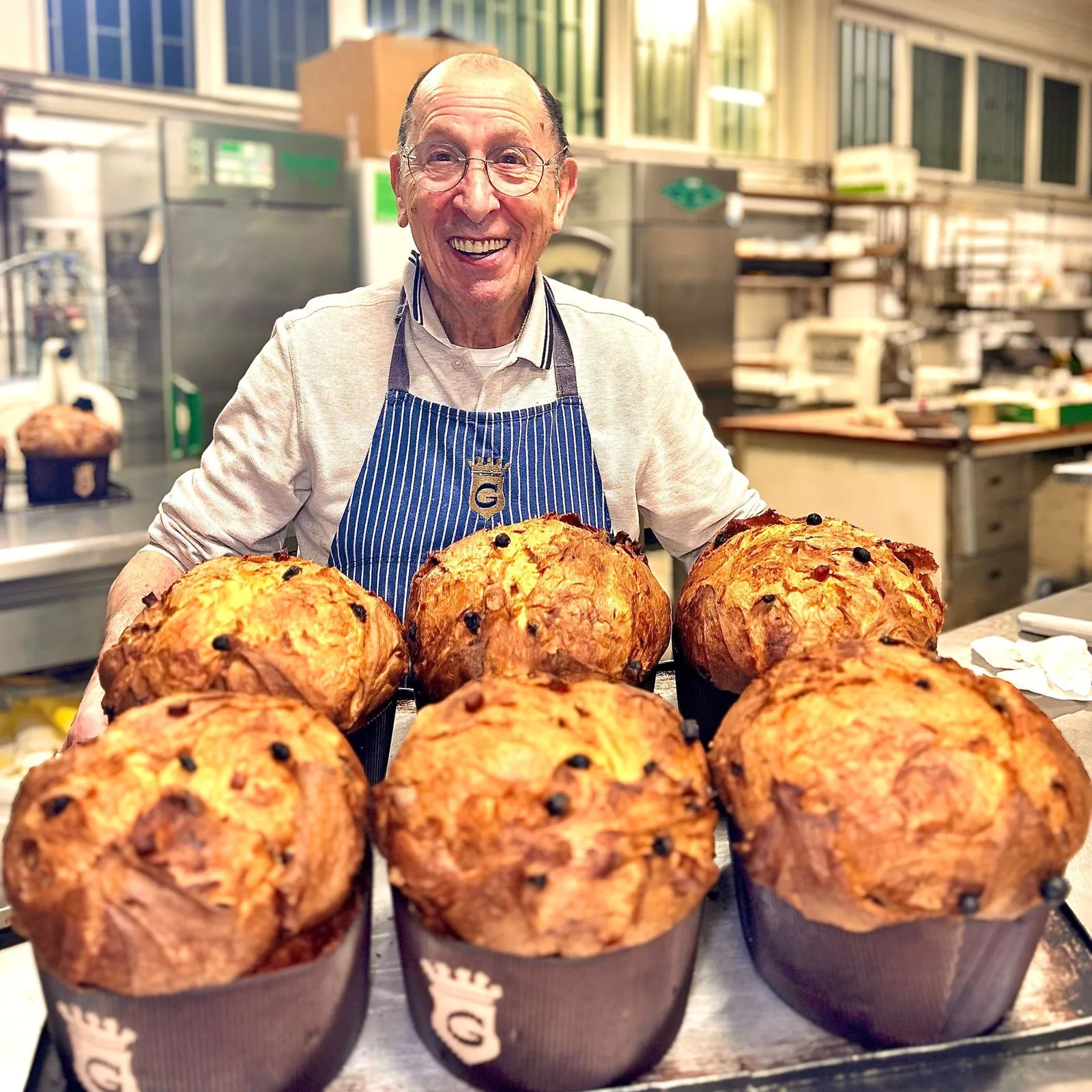 Un uomo con un grembiule blu tiene in mano un vassoio di muffin